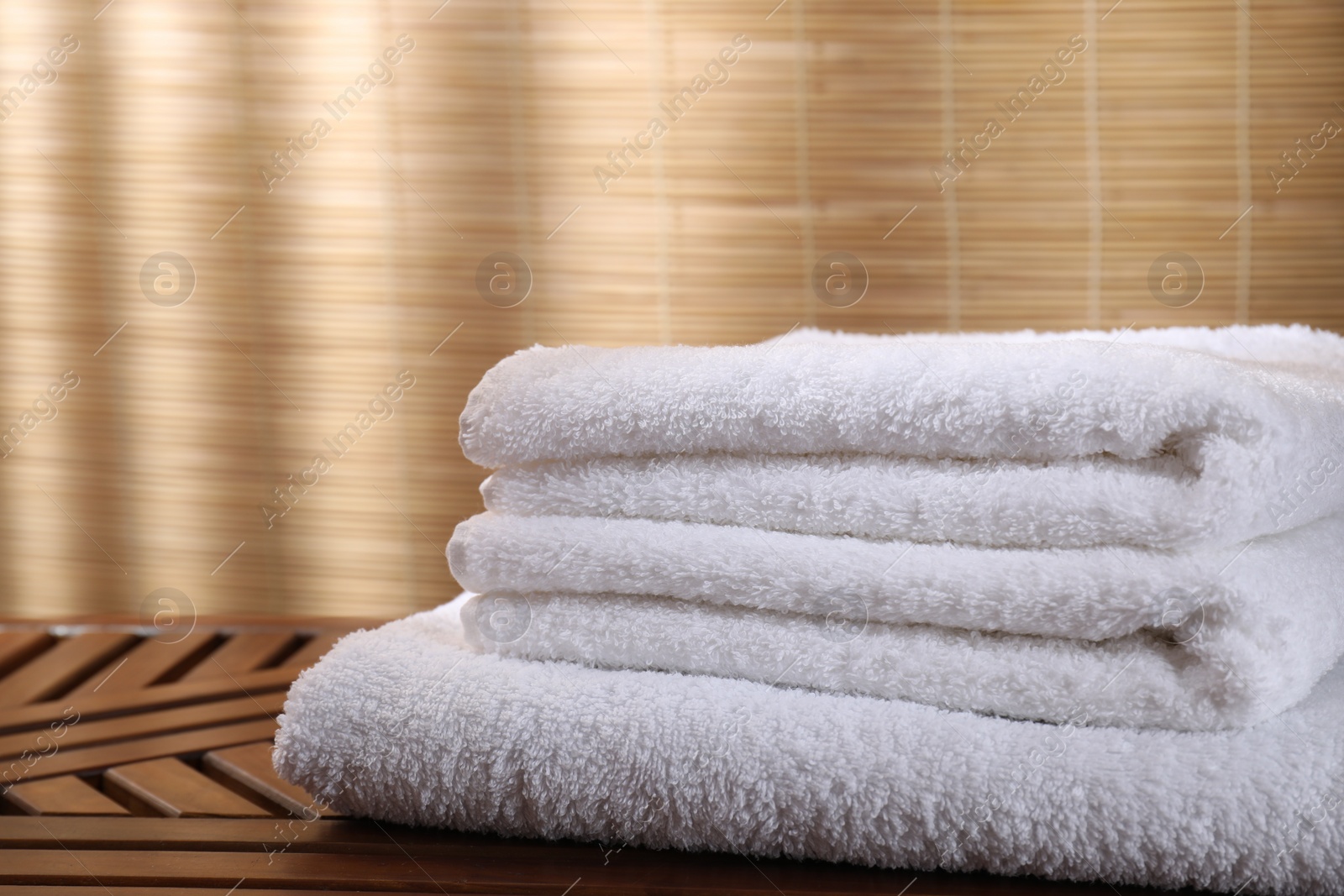 Photo of Stacked soft towels on wooden table indoors, closeup