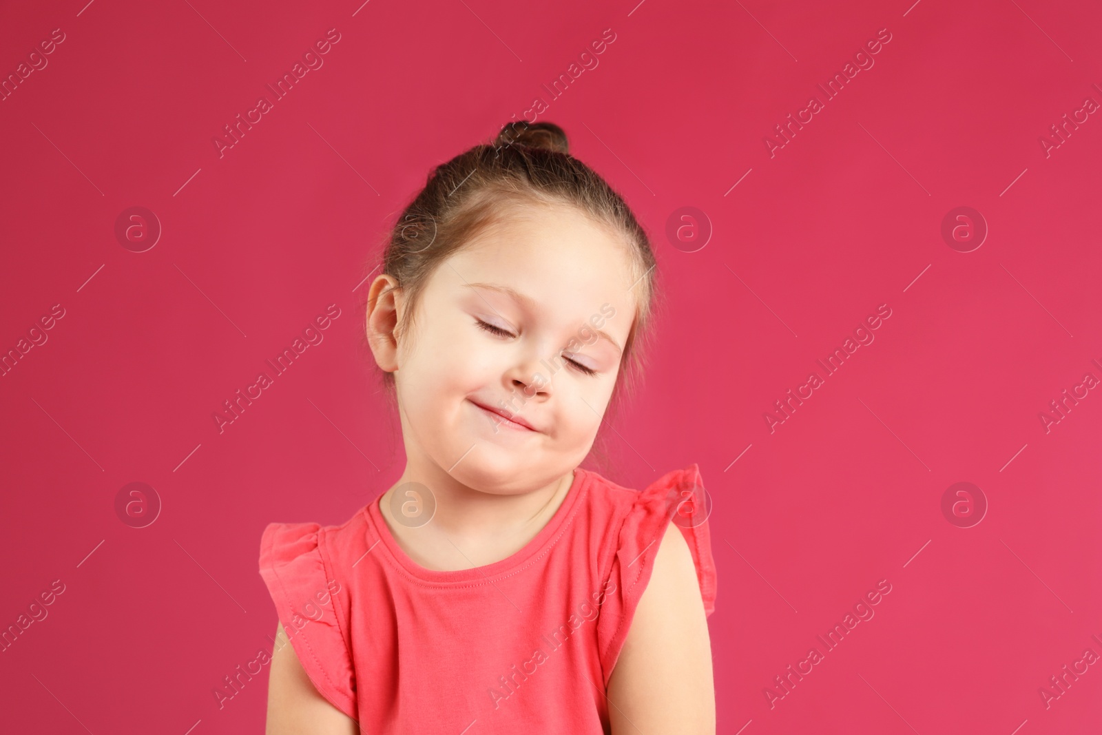 Photo of Portrait of cute little girl on pink background