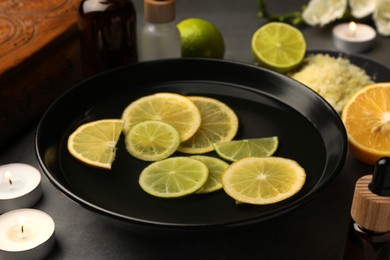 Photo of Bowlessential oil and lemons on grey table. Aromatherapy treatment