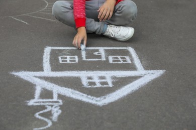 Photo of Child drawing house with chalk on asphalt, closeup