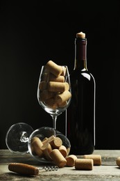 Bottle of wine and glasses with many corks on wooden table