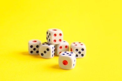 Photo of Many white game dices on yellow background, closeup