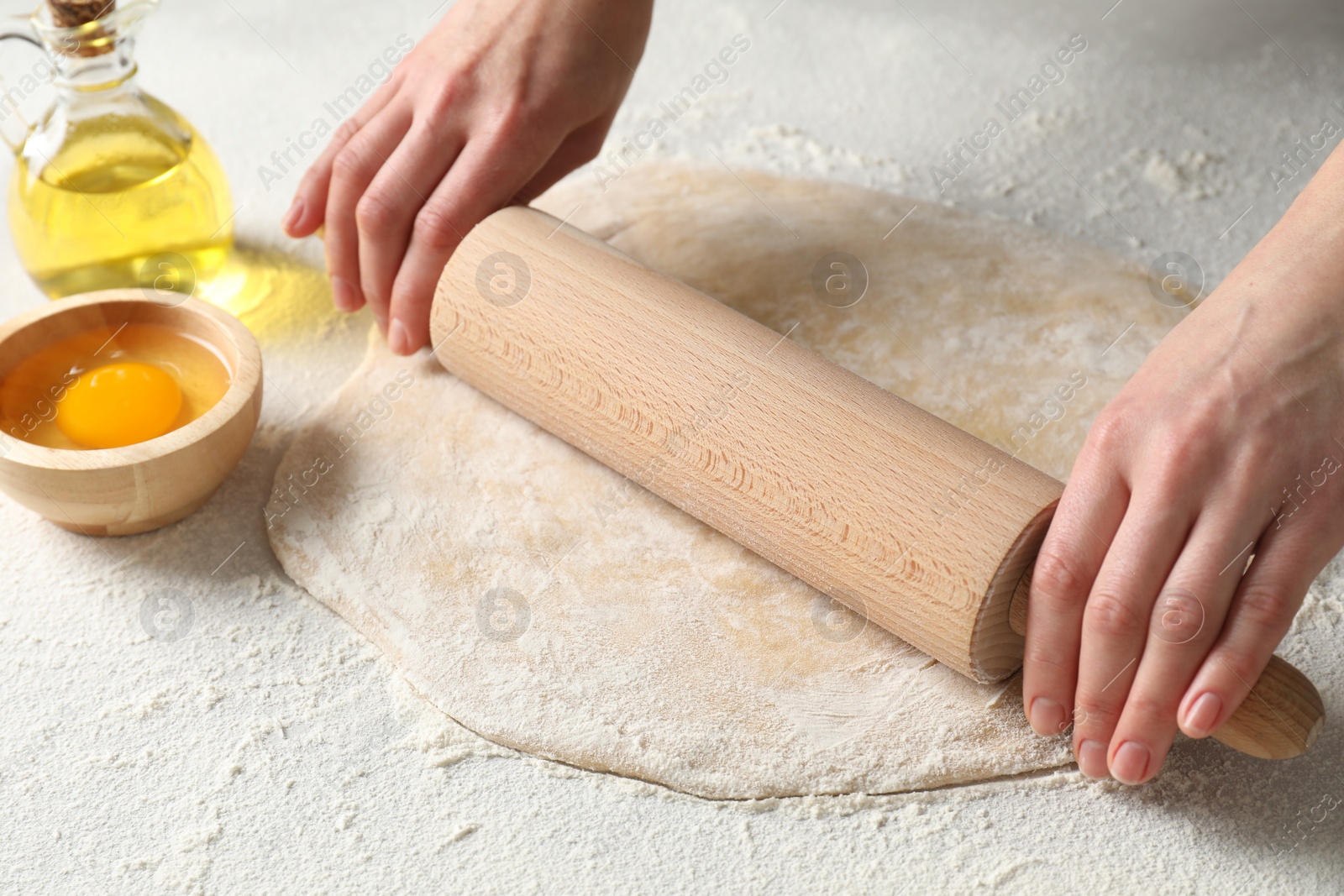 Photo of Woman rolling raw dough at table, closeup