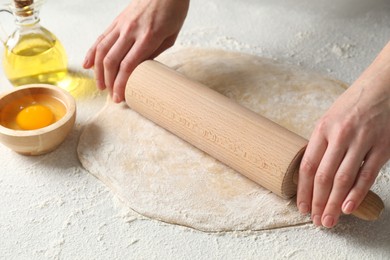 Photo of Woman rolling raw dough at table, closeup