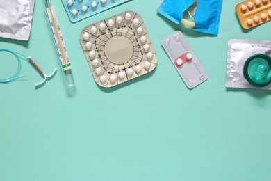 Photo of Contraceptive pills, condoms, intrauterine device and thermometer on turquoise background, flat lay with space for text. Different birth control methods