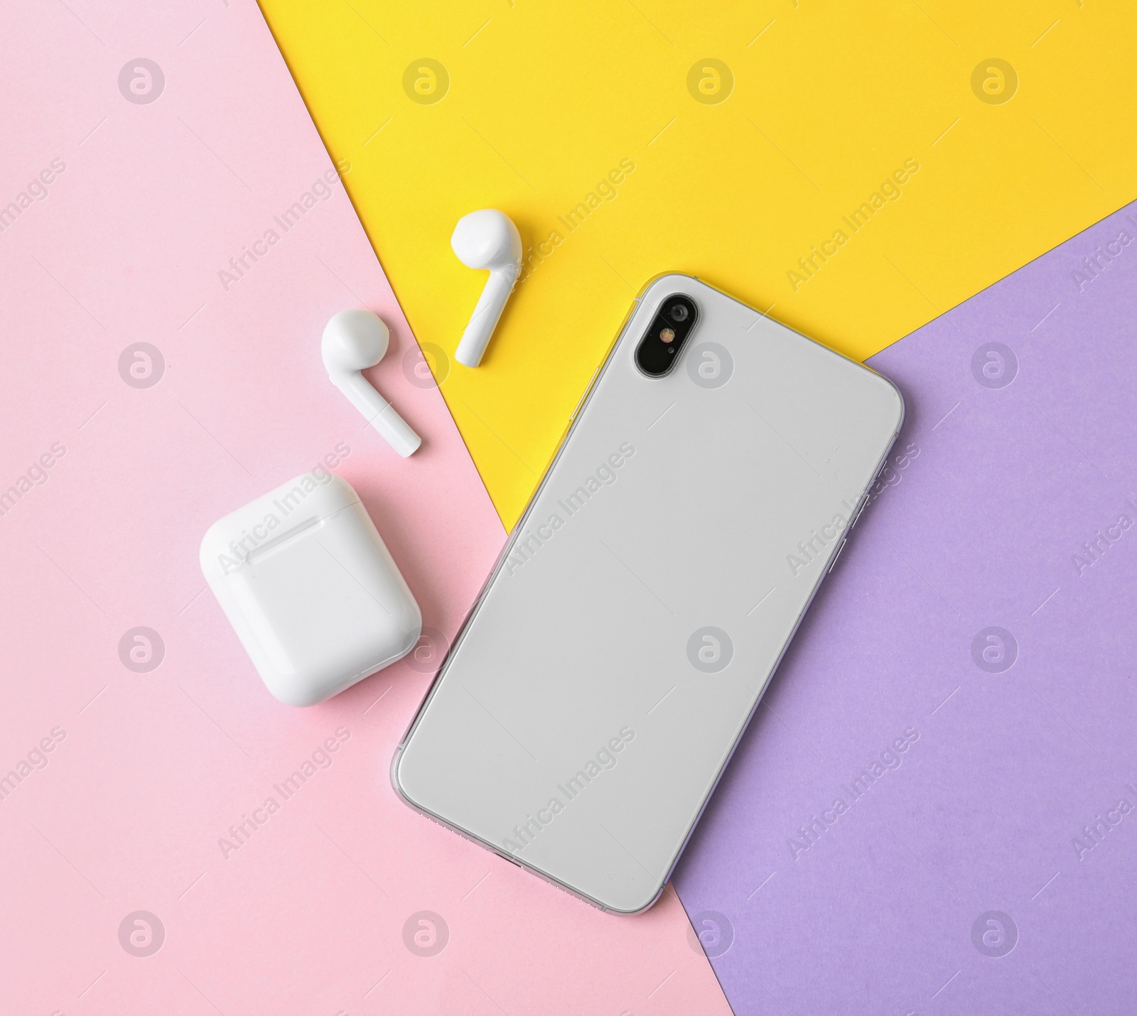 Photo of Wireless earphones, mobile phone and charging case on color background, flat lay