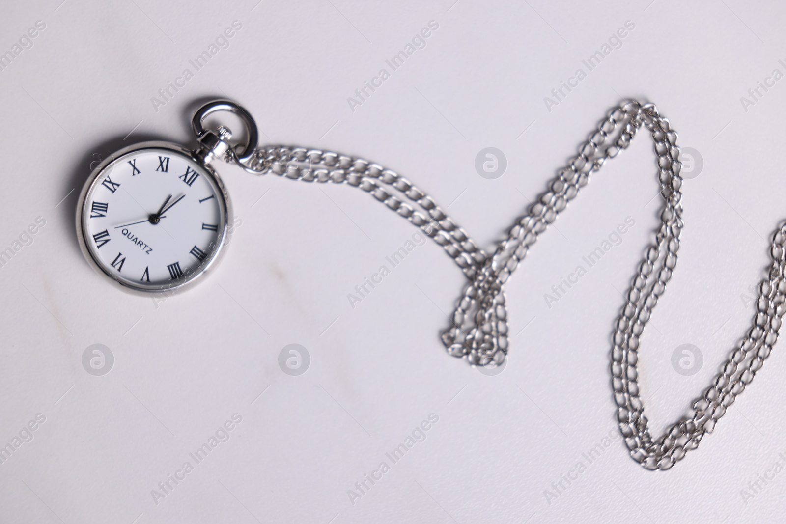 Photo of Silver pocket clock with chain on light table, top view