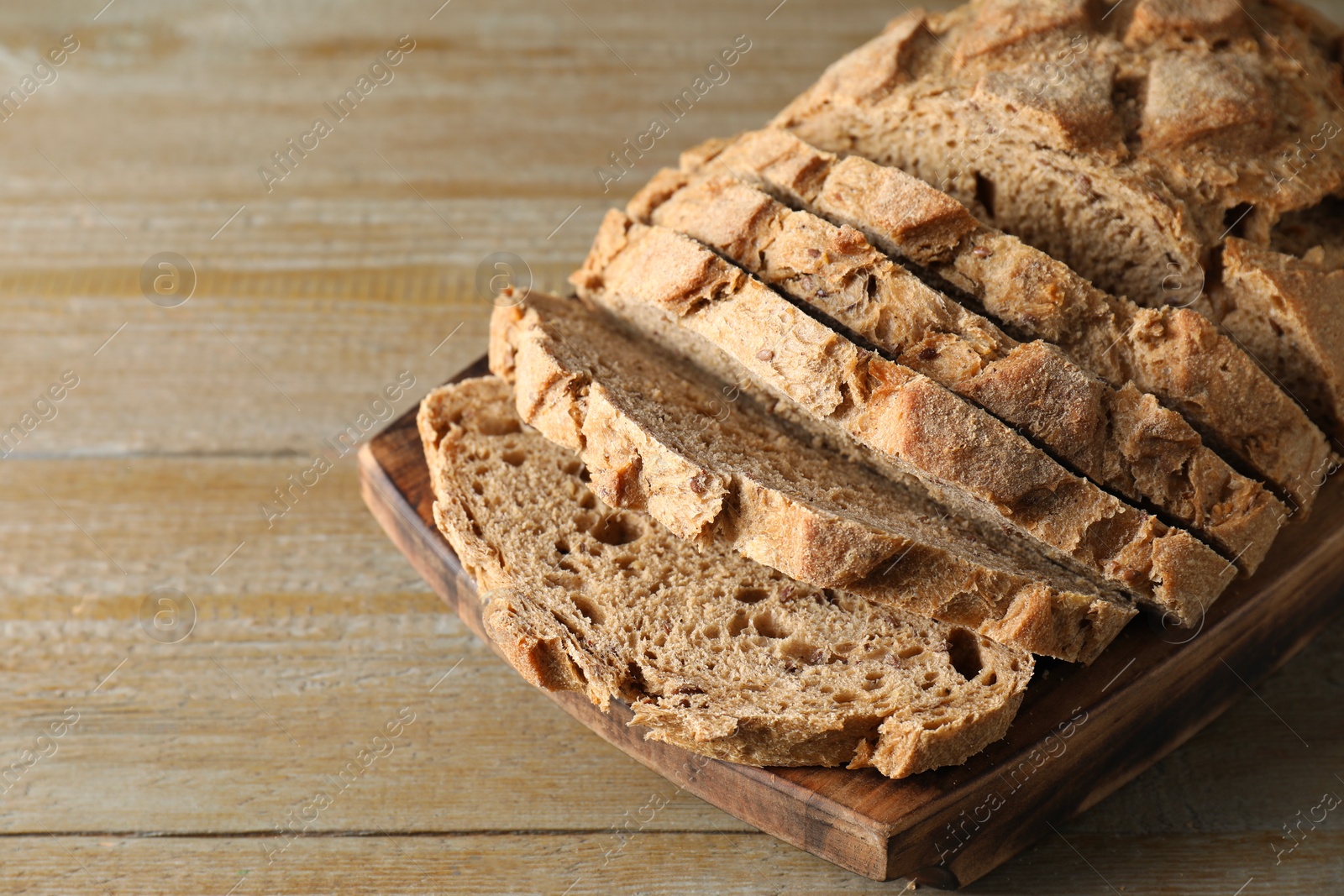 Photo of Freshly baked cut sourdough bread on wooden table, closeup. Space for text