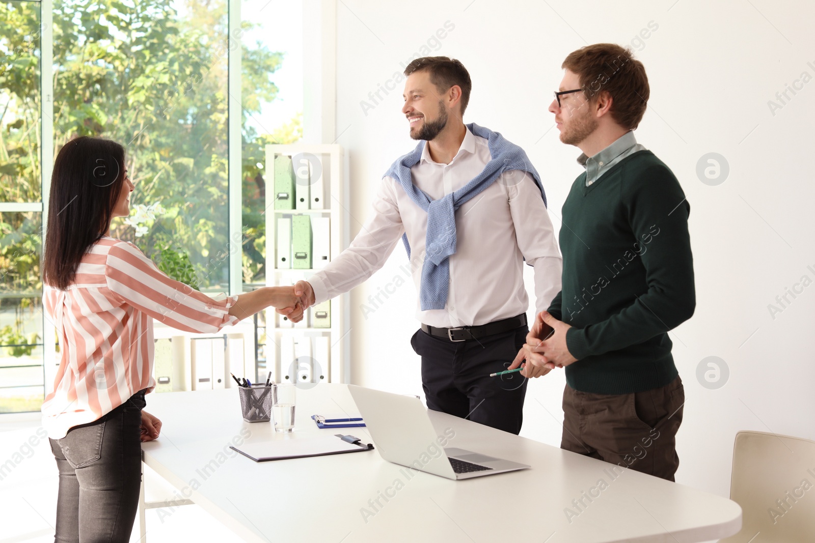 Photo of Human resources manager shaking hands with applicant during job interview in office