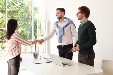 Human resources manager shaking hands with applicant during job interview in office