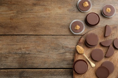 Delicious peanut butter cups on wooden table, flat lay. Space for text