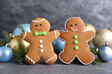 Photo of Gingerbread people and Christmas decor on grey table, closeup