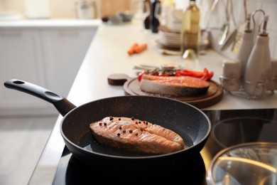Frying pan with tasty salmon steak on cooktop