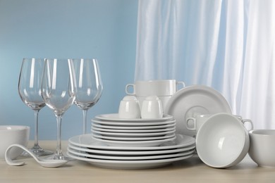 Set of clean dishware and glasses on light grey table