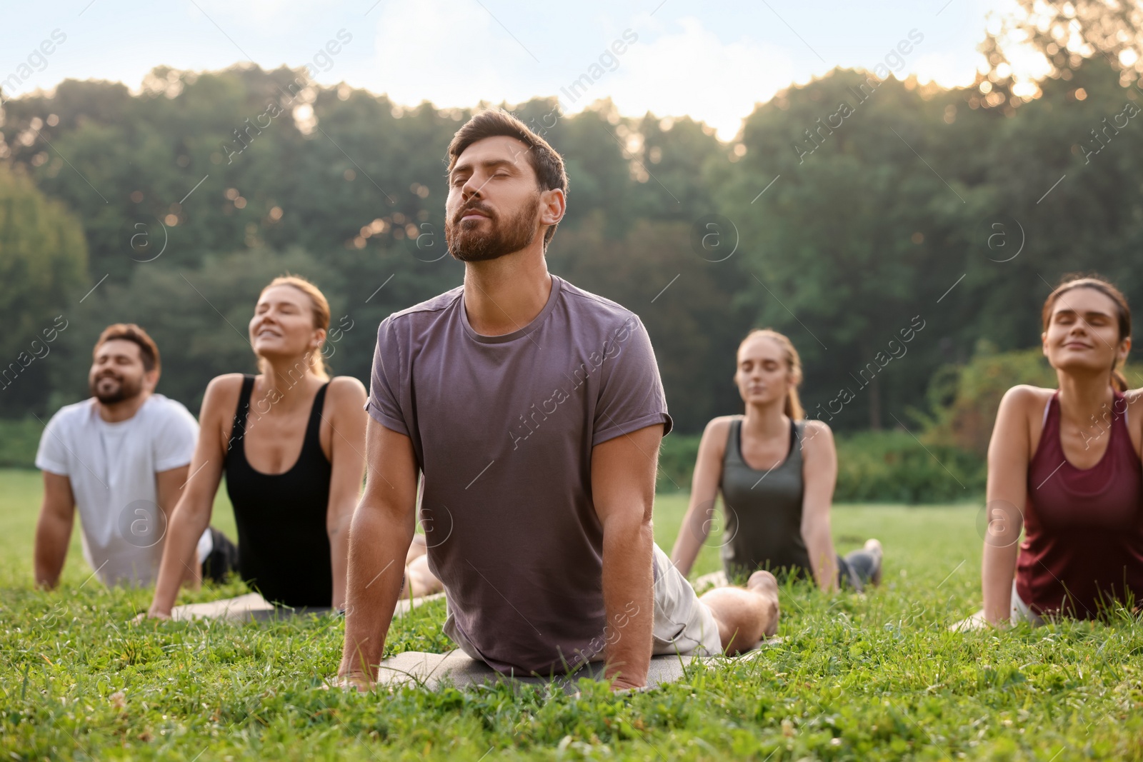 Photo of Group of people practicing yoga on mats outdoors