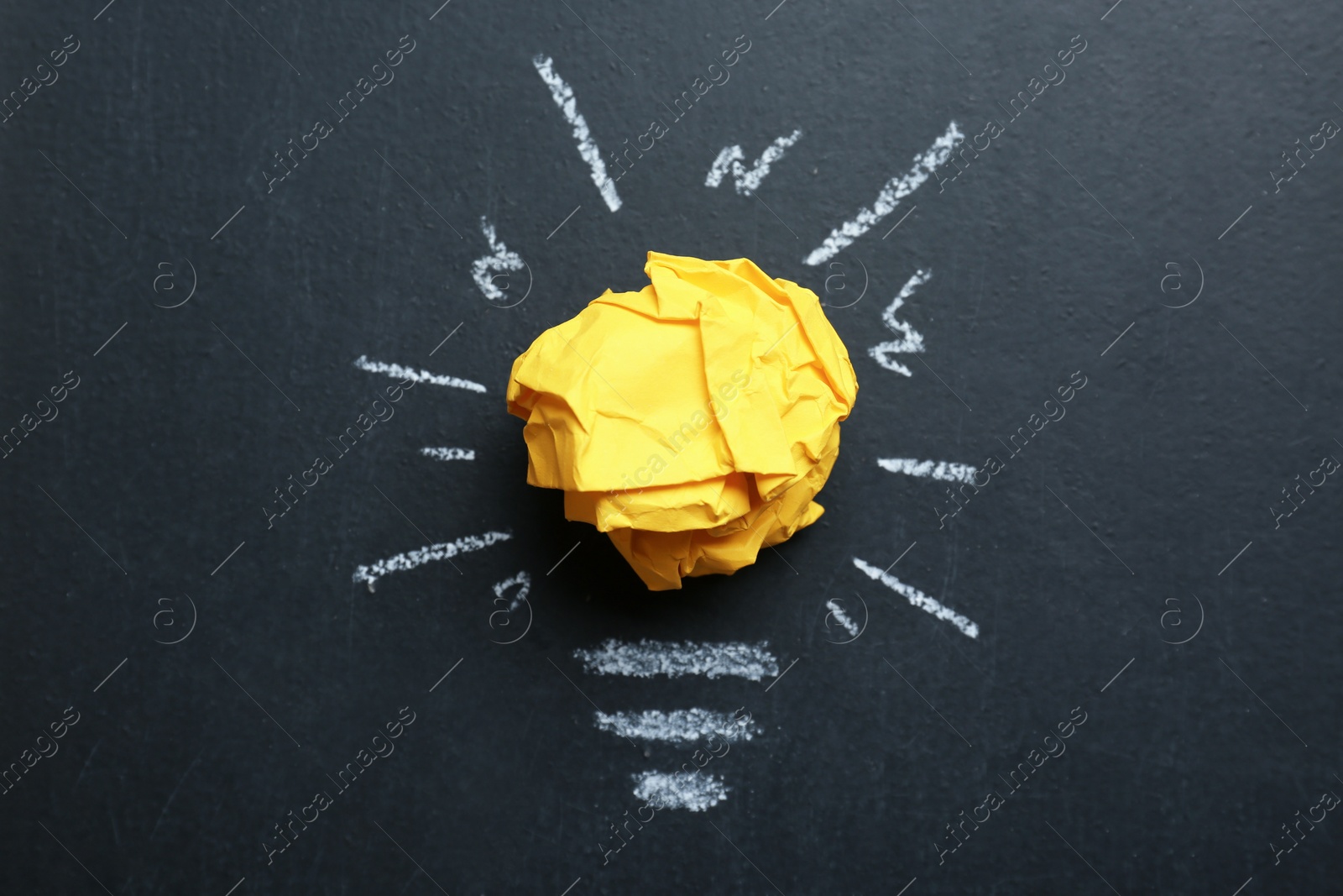 Photo of Composition with crumpled paper ball and drawing of lamp bulb on blackboard, top view. Idea concept