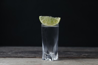 Photo of Shot of vodka with lime slice on wooden table