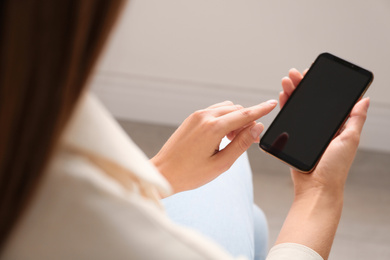 Photo of Young woman using modern smartphone indoors, closeup