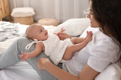 Photo of Happy young mother with her cute baby on bed at home