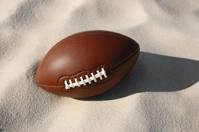 Photo of New leather American football ball on sand