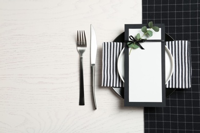 Photo of Stylish elegant table setting and blank card on wooden background, top view. Space for text