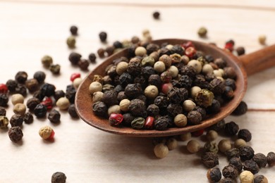 Photo of Aromatic spices. Different peppers in spoon on wooden table, closeup