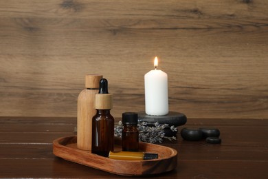 Aromatherapy products, burning candle and lavender on wooden table
