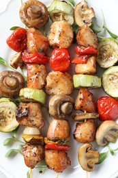 Photo of Delicious shish kebabs with vegetables and microgreens on white plate, top view