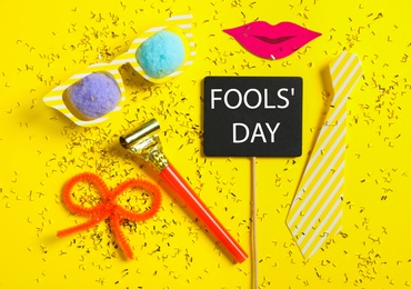 Different clown's accessories on yellow background, flat lay