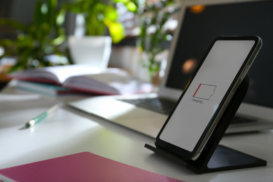 Modern workplace and smartphone charging with wireless pad, closeup