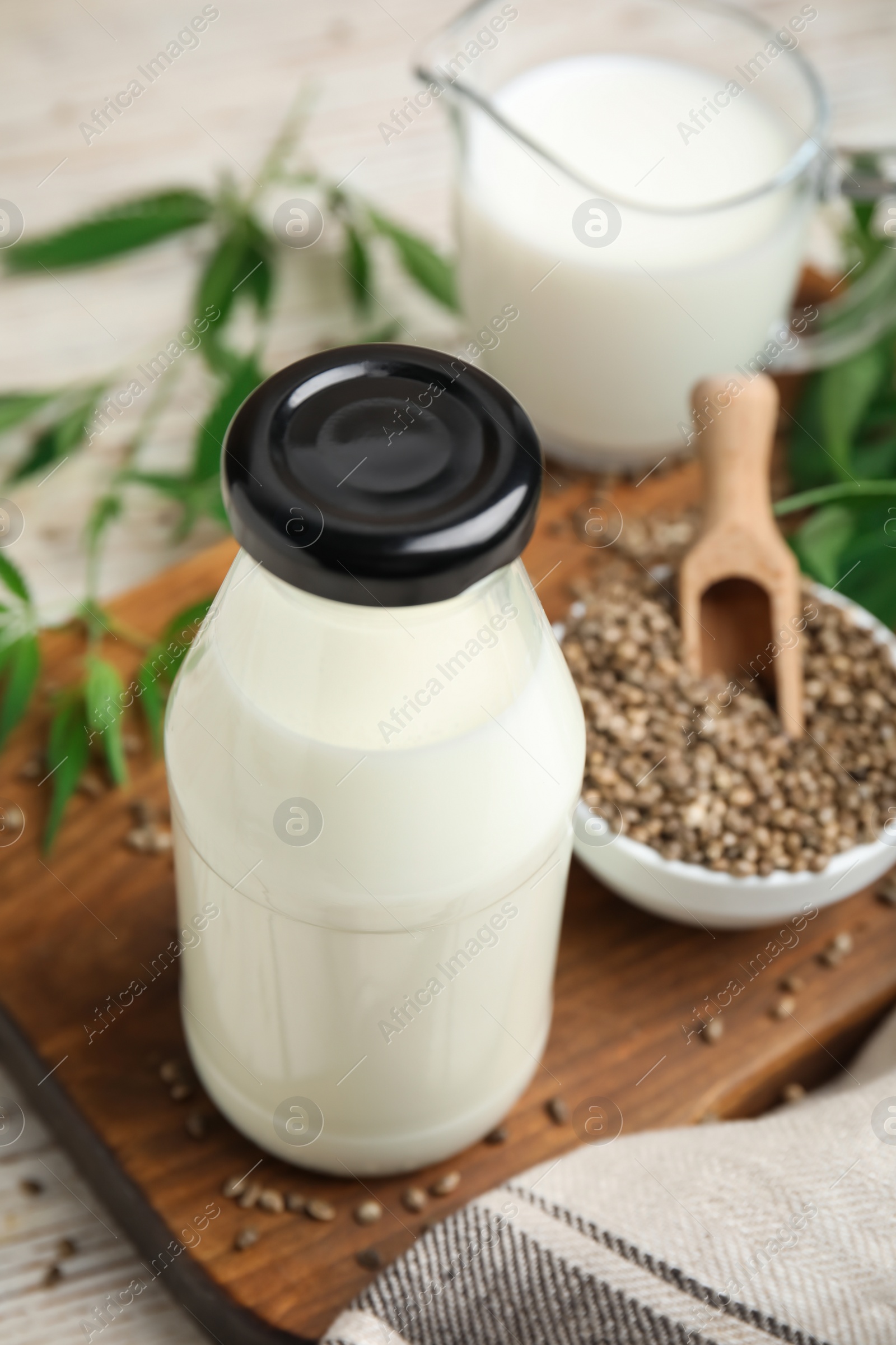 Photo of Glass bottle with hemp milk on wooden board, closeup