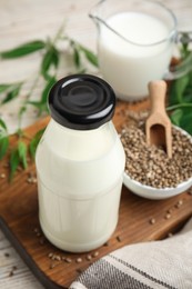 Glass bottle with hemp milk on wooden board, closeup