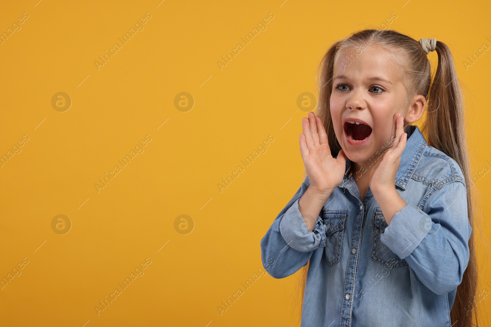 Photo of Special promotion. Little girl shouting to announce information on orange background. Space for text