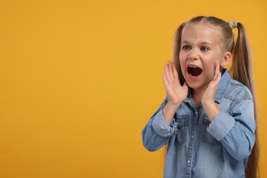 Photo of Special promotion. Little girl shouting to announce information on orange background. Space for text