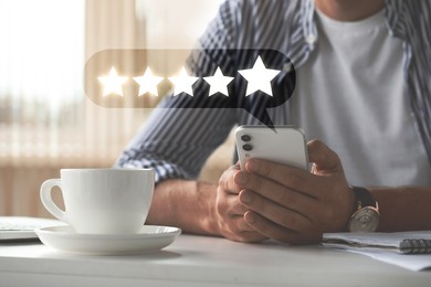 Image of Man leaving service feedback with smartphone at table, closeup. Stars over device