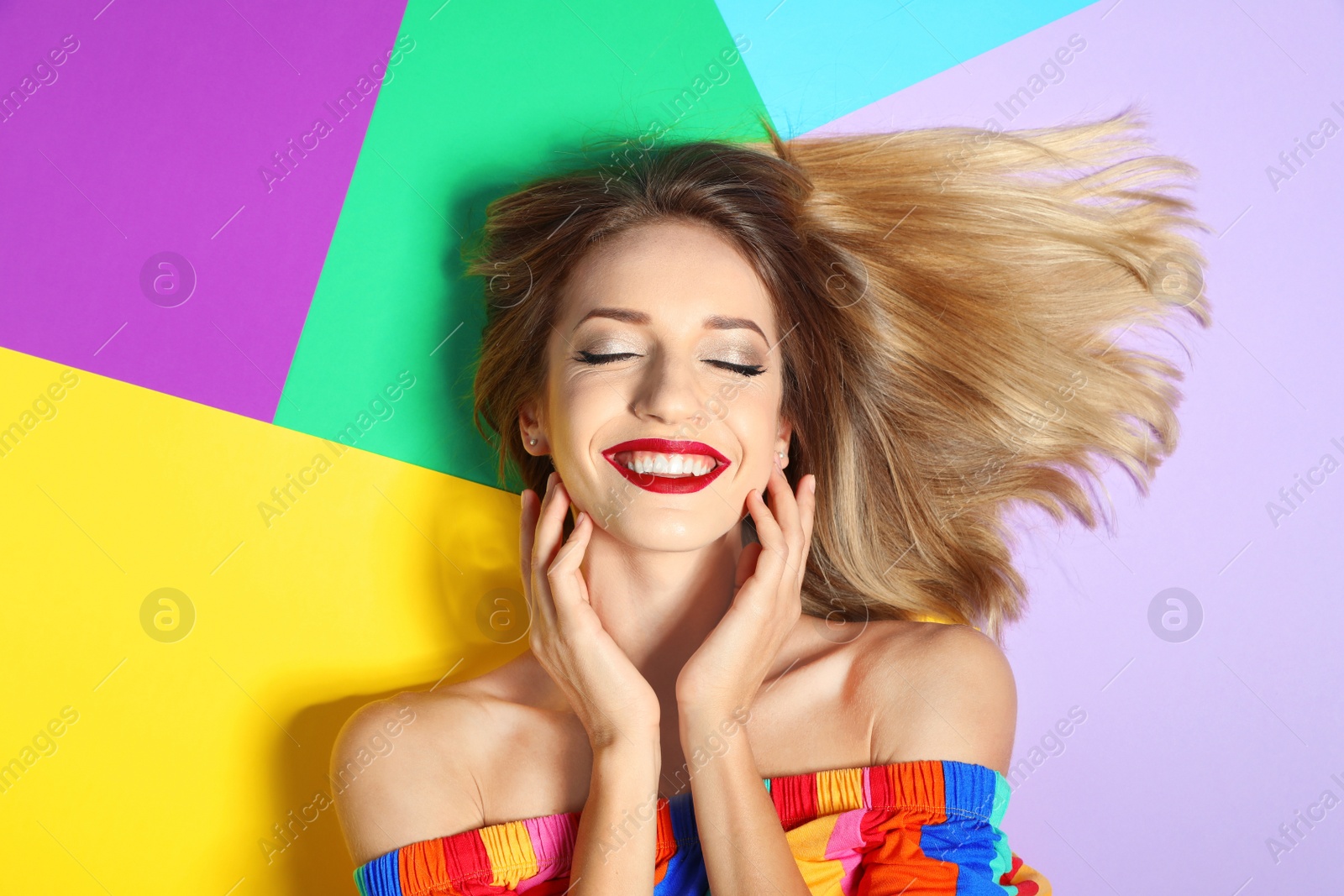 Photo of Beautiful young woman with healthy long blonde hair on color background, top view