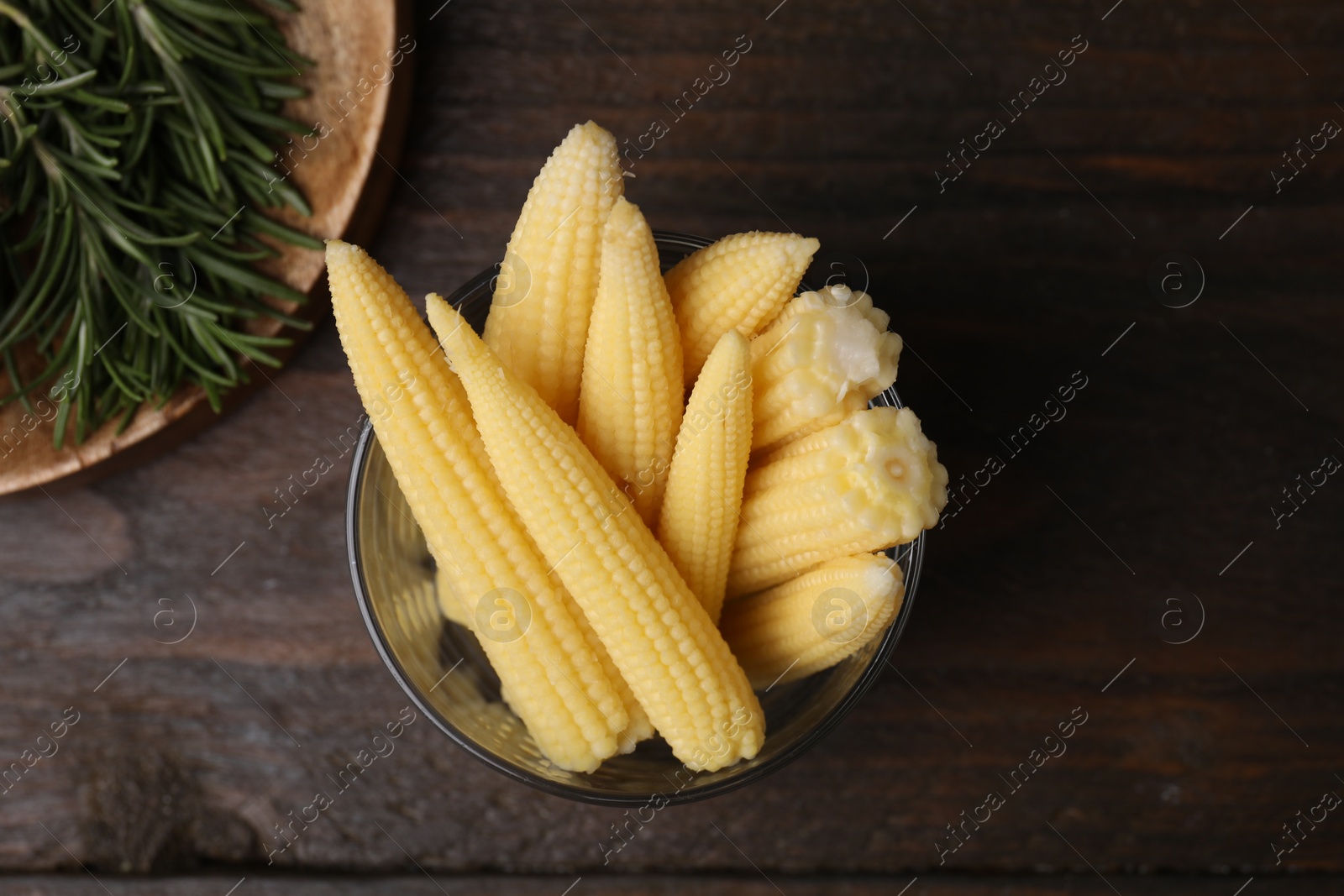 Photo of Tasty fresh yellow baby corns in glass on wooden table, top view