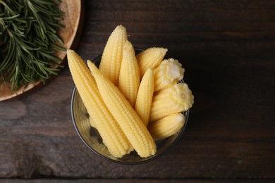 Tasty fresh yellow baby corns in glass on wooden table, top view