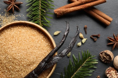 Photo of Different aromatic spices and fir branches on dark textured table, flat lay