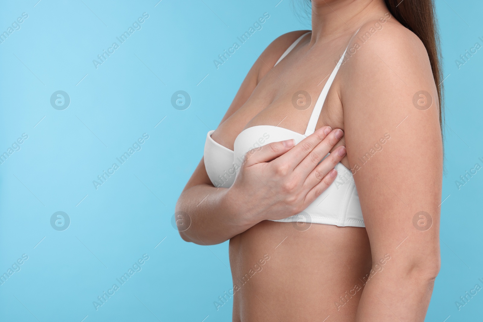 Photo of Mammology. Woman in bra doing breast self-examination on light blue background, closeup and space for text