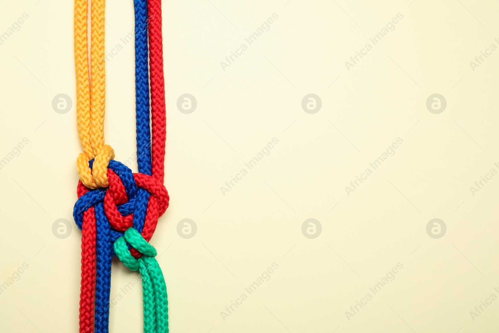 Photo of Top view of colorful ropes tied together on beige background, space for text. Unity concept