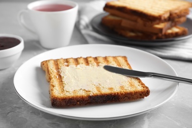 Photo of Tasty toast with butter served on grey marble table, closeup