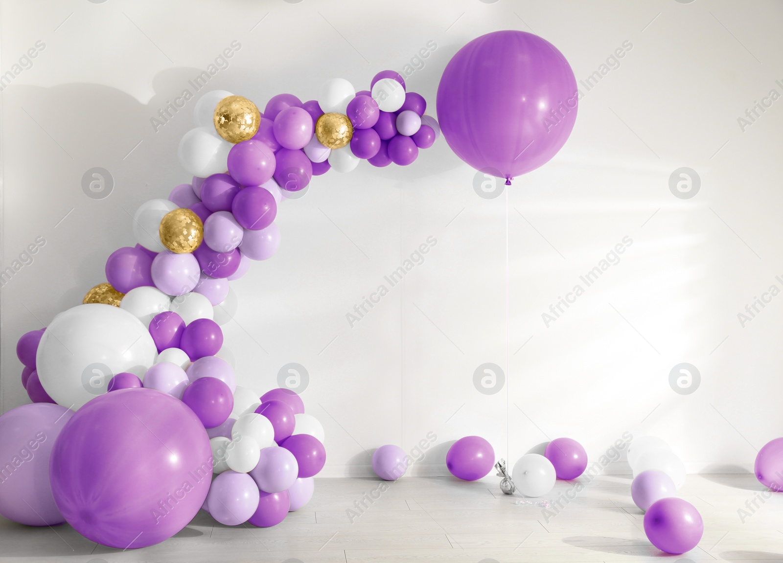 Image of Balloon garland near white wall in room. Festive decor