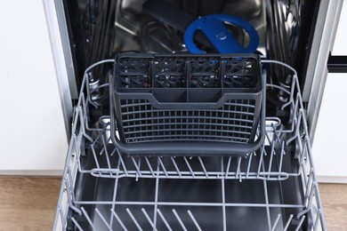 Photo of Open clean empty dishwasher indoors, closeup. Home appliance