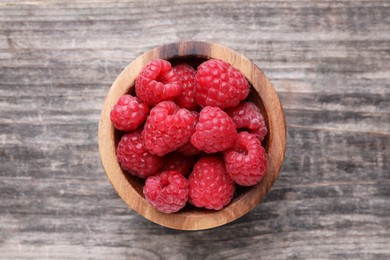 Tasty ripe raspberries in bowl on wooden table, top view