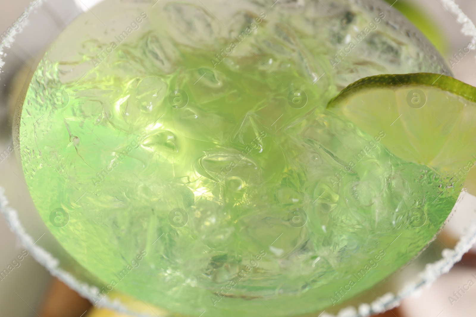 Photo of Delicious Margarita cocktail with ice cubes in glass and lime, closeup