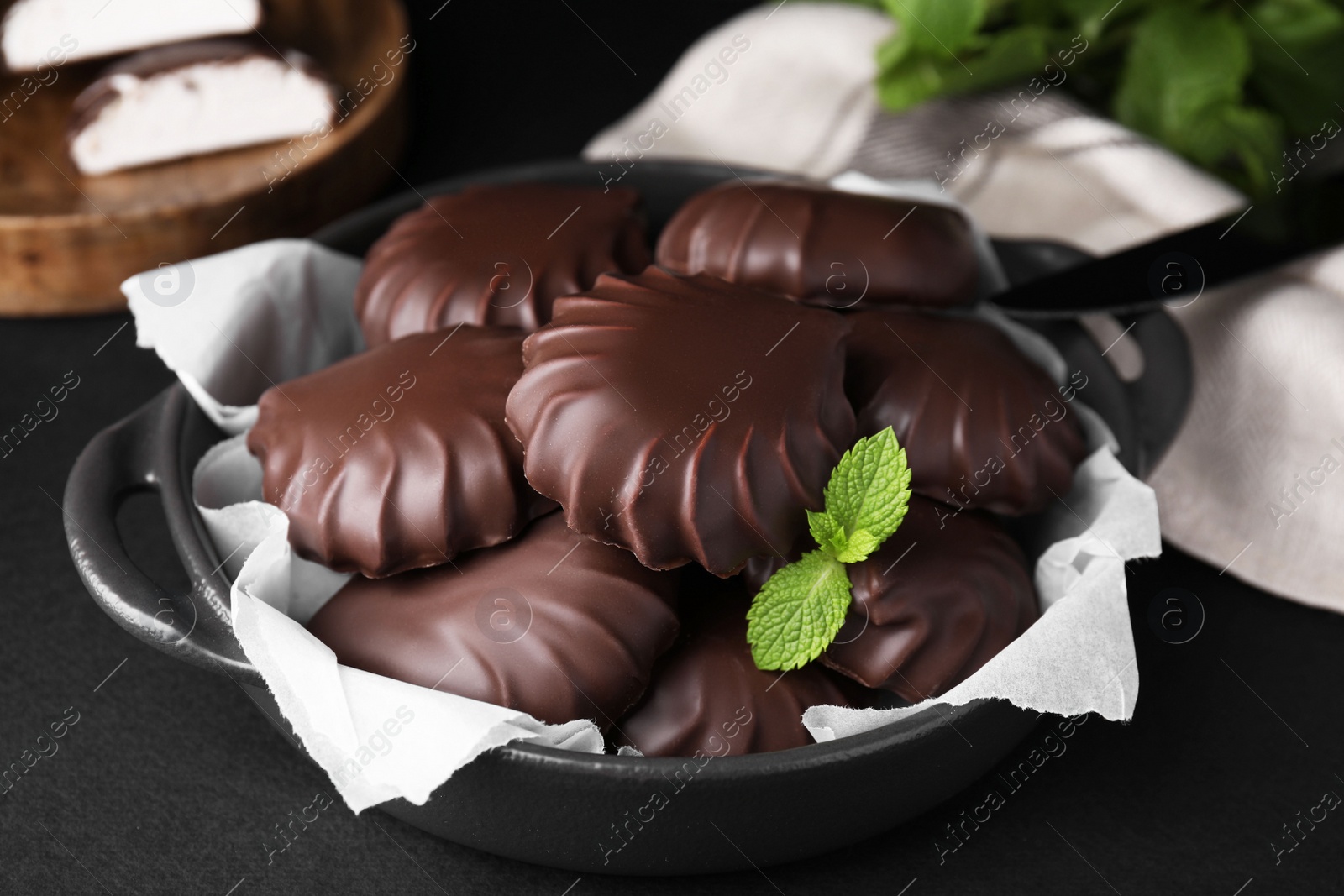 Photo of Delicious chocolate covered marshmallows with mint on black table