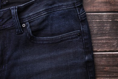 Jeans with pocket on wooden background, top view