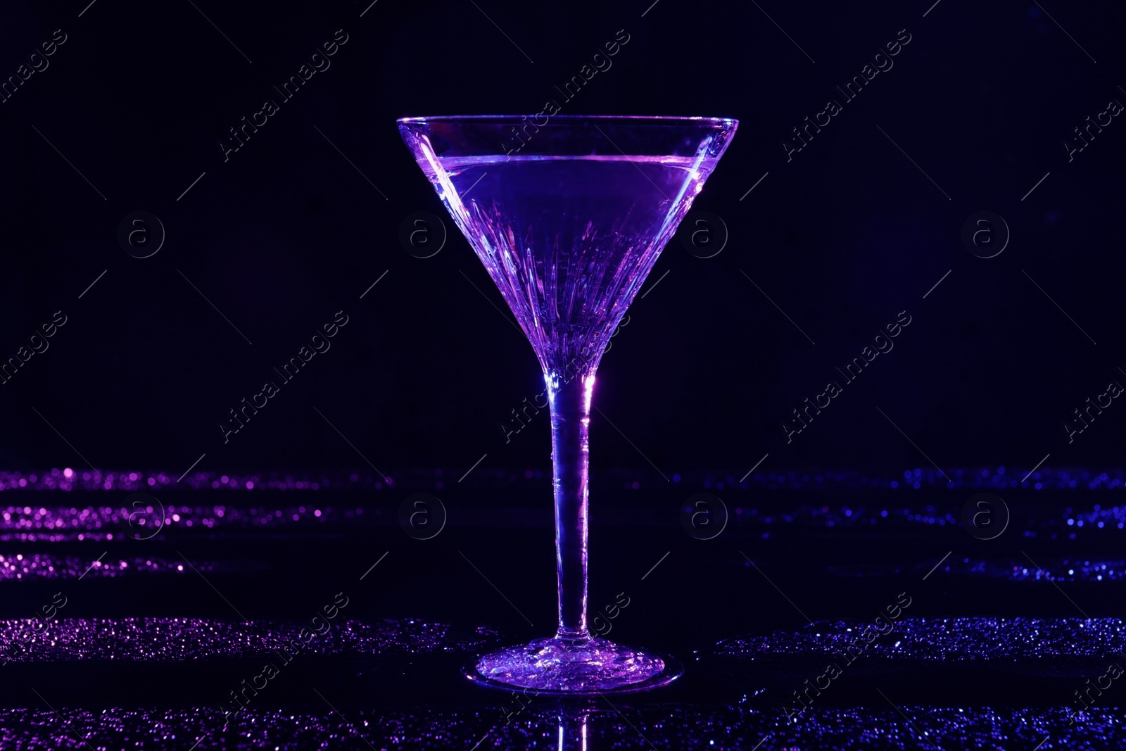 Photo of Glass of martini in neon lights on dark blue background