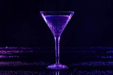 Glass of martini in neon lights on dark blue background